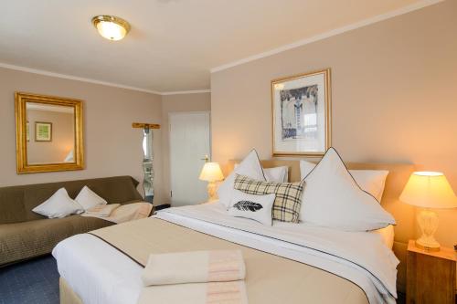 a bedroom with a large white bed and a couch at Landhaus Ambiente in Munich