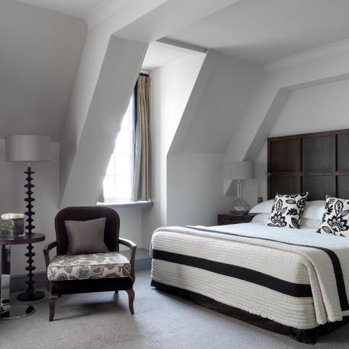 a bedroom with a bed and a chair at The Bloomsbury Hotel in London