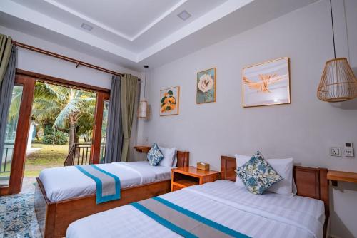 two beds in a room with a window at Ganesha Kampot Resort in Kampot