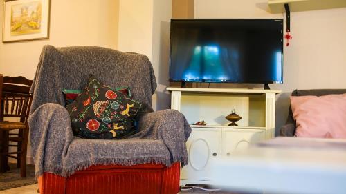 a living room with a chair and a television at Artemis Apartment,Beach two-bedroom in Artemida