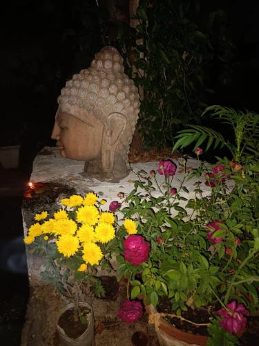 a statue of a head sitting next to flowers at Hotel Zen in Khajurāho