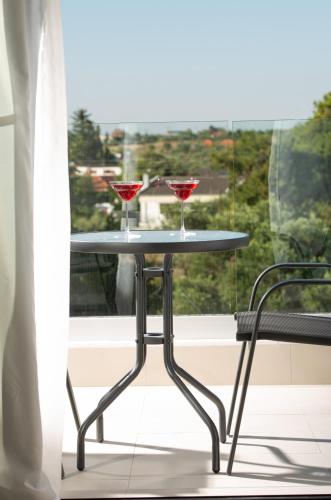 two wine glasses on a table in front of a window at Light Blue Hotel in Nea Kalikratia