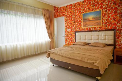 a bedroom with a bed in a room with orange wallpaper at Griya Kayana Inn and Villas in Bogor