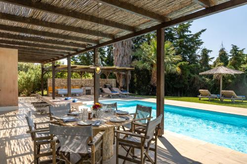 a patio with a table and chairs next to a swimming pool at Sunny Villas in Klísmata