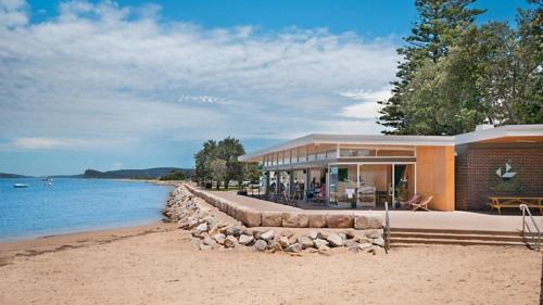 a building on a beach next to the water at Waterview Retreat - Blackwal in Blackwall