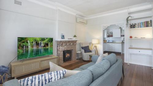 a living room with a couch and a tv at Coast Along - Ettalong Beach in Ettalong Beach