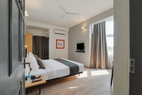 ein Hotelzimmer mit einem Bett und einem Fenster in der Unterkunft Super Townhouse 124 Srm Kuppakonam Pudur in Coimbatore