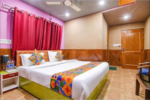 a bedroom with a large bed and red curtains at Hotel City Plaza in Dharamshala