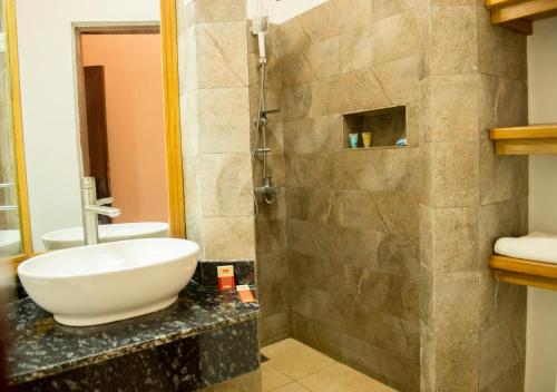 a bathroom with a sink and a shower at Hotel Safari Gate in Bujumbura