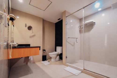 uma casa de banho com um chuveiro e um WC. em Surabaya Suites Hotel Powered by Archipelago em Surabaia