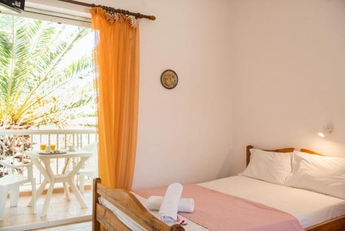 a bedroom with a bed and a balcony with a table at Kalofonos Studios in Laganas
