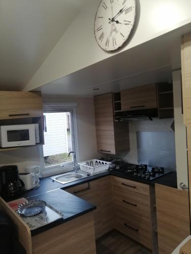 a kitchen with a large clock on the wall at MHVACANCES LOUENT PLUSIEURS MOBILHOMES DANS CAMPING 4 ETOILES PROCHE CHATEAUX et ZOO BEAUVAL in Onzain