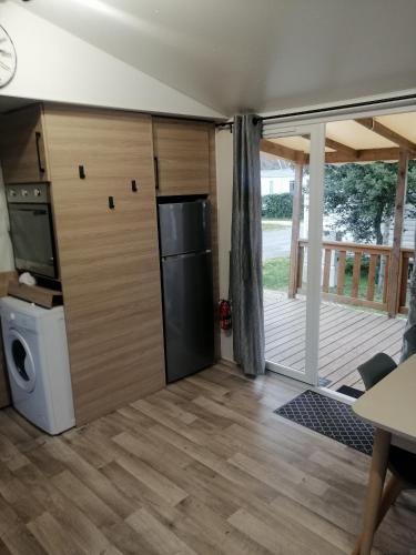 a kitchen with a refrigerator and a door to a deck at MHVACANCES LOUENT PLUSIEURS MOBILHOMES DANS CAMPING 4 ETOILES PROCHE CHATEAUX et ZOO BEAUVAL in Onzain
