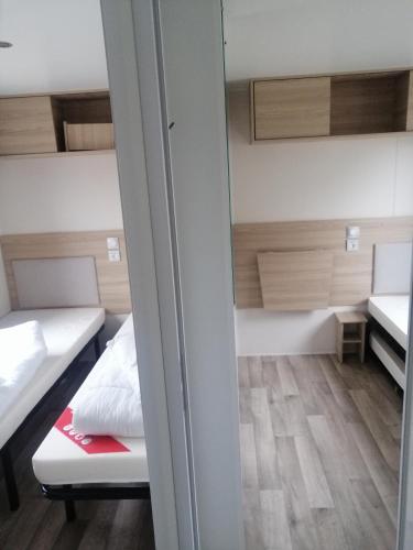 a small room with two beds and a mirror at MHVACANCES LOUENT PLUSIEURS MOBILHOMES DANS CAMPING 4 ETOILES PROCHE CHATEAUX et ZOO BEAUVAL in Onzain
