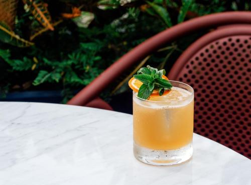 a drink sitting on a table with an orange slice at The Standard, Bangkok Mahanakhon in Bangkok