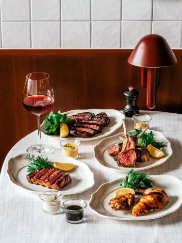 a table with four plates of food and a glass of wine at The Standard, Bangkok Mahanakhon in Bangkok