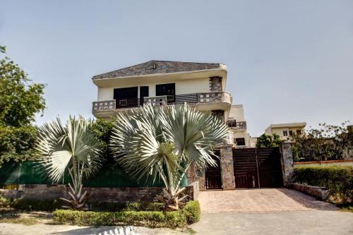 a house with two palm trees in front of it at OYO Home Spacious Studio Sector 21-a Faridabad in Faridabad