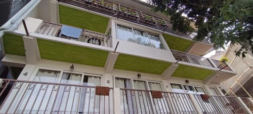 a white and green building with a balcony at Tito's Homestay in Kalimpong