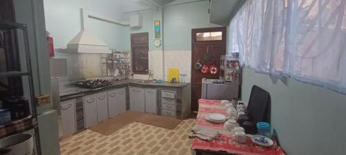 a kitchen with white cabinets and a table in it at Tito's Homestay in Kalimpong