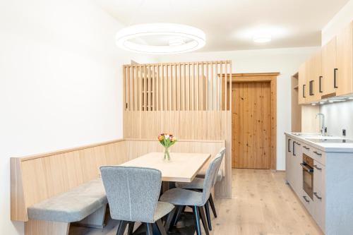 a kitchen with a wooden table with chairs and a vase of flowers at Dorfresort Kitzbühel by ALPS RESORTS in Reith bei Kitzbühel