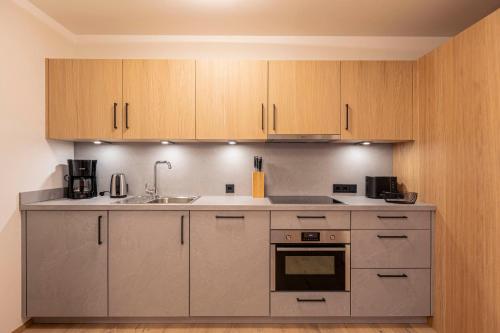 a kitchen with stainless steel appliances and wooden cabinets at Dorfresort Kitzbühel by ALPS RESORTS in Reith bei Kitzbühel