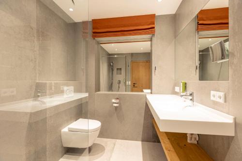 a bathroom with two sinks and a toilet and a mirror at Dorfresort Kitzbühel by ALPS RESORTS in Reith bei Kitzbühel