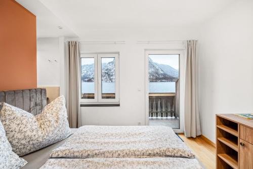 um quarto com uma cama e duas janelas em Hallstatt Lakeside Top 4 - Zimmer mit Balkon em Hallstatt