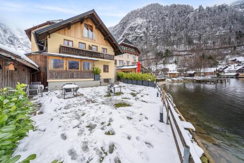 a house in the snow next to a body of water at Hallstatt Lakeside Top 4 - Zimmer mit Balkon in Hallstatt