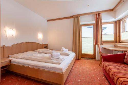 a hotel room with a bed and a couch at Dorfresort Kitzbühel by ALPS RESORTS in Reith bei Kitzbühel