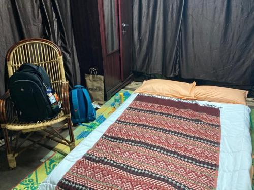 スルタン・バザリーにあるLotus Jewel Forest Campingのベッドルーム1室(ベッド1台、バックパック、椅子付)