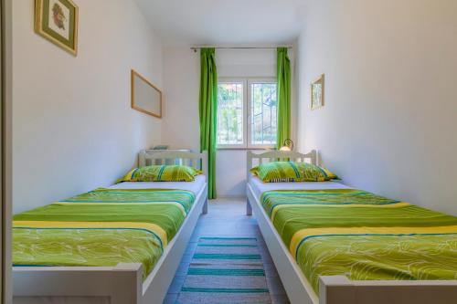 2 camas en una habitación con cortinas verdes en Apartman Maša, en Dramalj