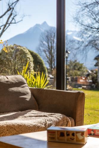 a couch sitting in front of a large window at Lodge ou Gîte de caractére avec jaccuzi spa piscine in Argelès-Gazost