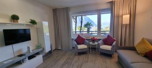 a living room with a couch and chairs and a television at Adele's Apartment in Bissone