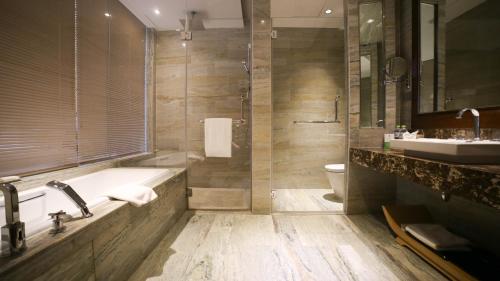 a bathroom with a tub and a toilet and a sink at Hai Tian Expo Hotel in Qingdao