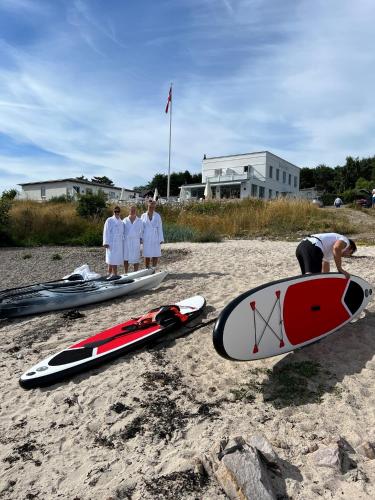 a group of people standing on a beach with surfboards at Melsted Badehotel in Gudhjem