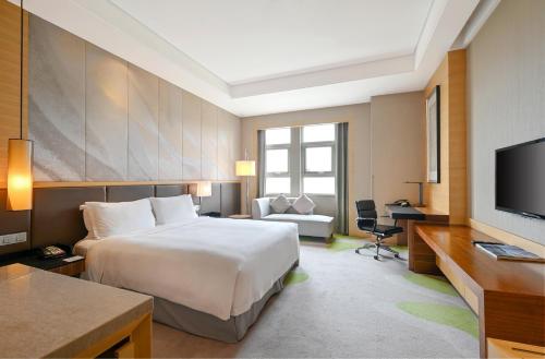 um quarto de hotel com uma cama grande e uma televisão em Holiday Inn Qingdao Expo, an IHG Hotel em Qingdao