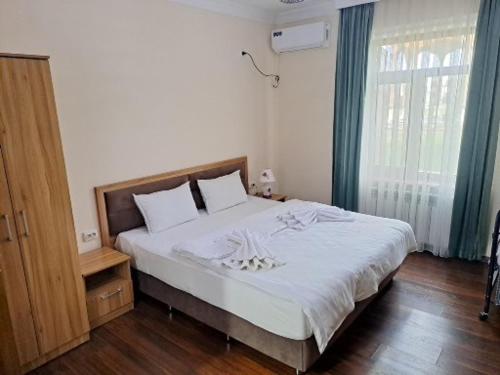 a bedroom with a large bed with white sheets and a window at Hotel SUZUK-OTA in Tashkent