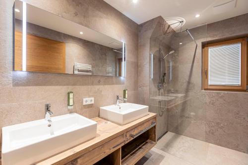 a bathroom with two sinks and a mirror and a shower at Dorfresort Kitzbühel by ALPS RESORTS in Reith bei Kitzbühel