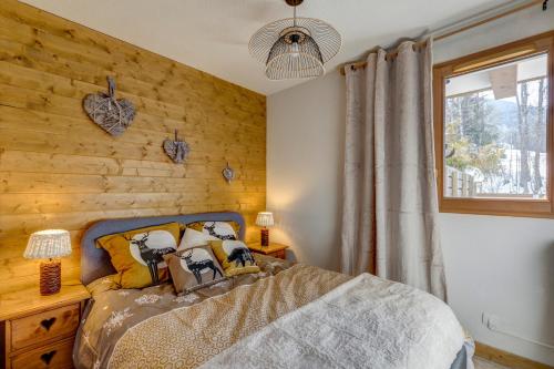 a bedroom with a wooden accent wall and a bed at Le Flocon de Neige - Appt cosy avec terrasse in Flumet