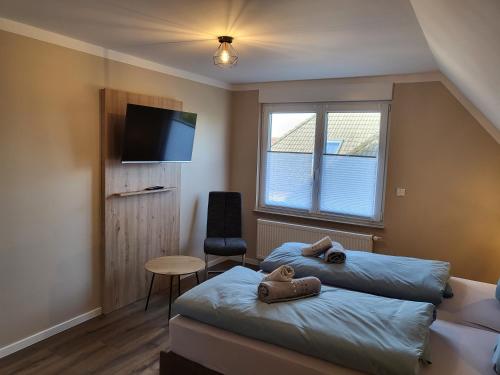 a bedroom with two beds and a tv and a chair at Krokusstr. 27A, Norden-Norddeich in Norden