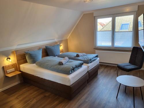 a bedroom with two beds and a chair at Krokusstr. 27A, Norden-Norddeich in Norden