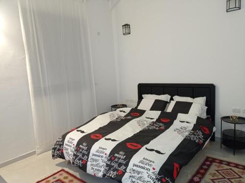 a bed with a black and white comforter and pillows at צימר ברחובות- Tara ארוח Tzimmer יש ממד במתחם in Rechovot