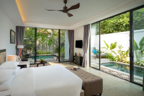 a bedroom with a large white bed and a pool at Eightfold Urban Resort in Siem Reap