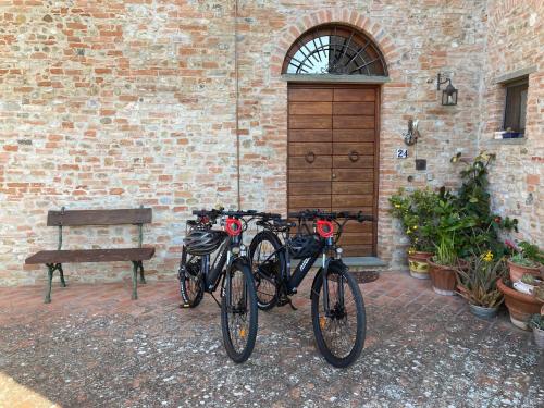 duas bicicletas estacionadas ao lado de um edifício de tijolos com um banco em Podere Sanripoli em Montespertoli