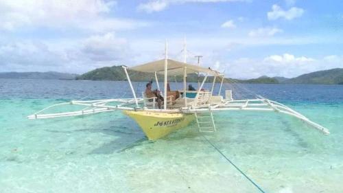 two people sitting on a boat in the water at NaturesWay/TRAVELCORON in Coron