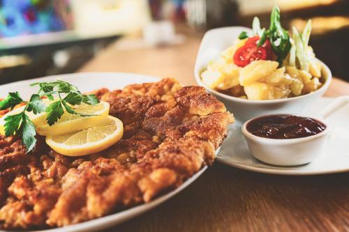 a plate of food on a wooden table with food at Das Reinisch Hotel - near Vienna Airport in Schwechat