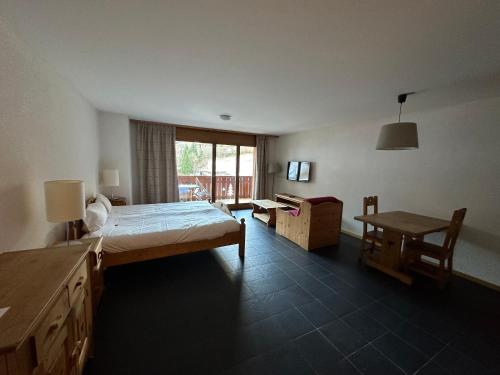 um quarto com uma cama, uma secretária e uma mesa em Mountain River Appart em Val dʼIlliez