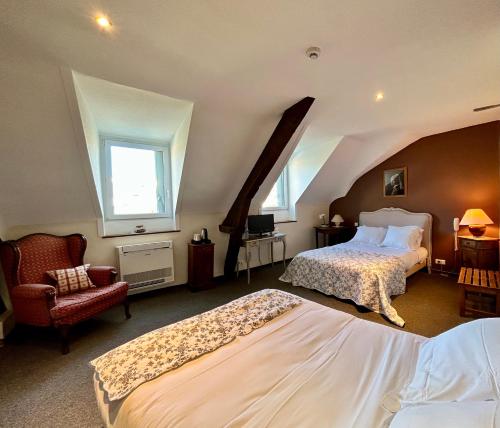 a large bedroom with two beds and a chair at Logis Hôtel Teyssier in Uzerche