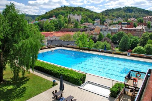 a large swimming pool with a city in the background at Rezidence Čertovka in Karlovy Vary