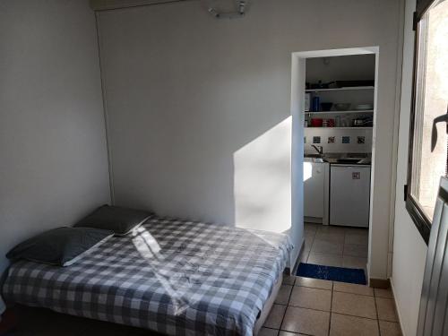 une petite chambre avec un lit et une cuisine dans l'établissement studio charmant et calme villeneuve les avignon entrée et cour indépendantes climatisation piscine parking, à Villeneuve-lès-Avignon